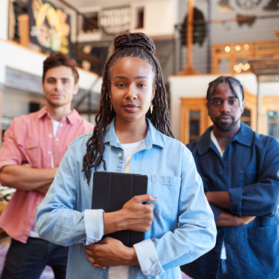 Portrait Of Multi-Cultural Sales Team In Fashion Store In Front Of Clothing Display